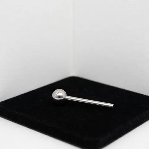 Piercing boule en acier inoxydable posé sur un tissu noir avec des reflets subtils, présenté dans un coin blanc pour une utilisation commerciale.