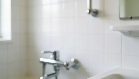Arrière-plan de salle de bain avec carreaux blancs, robinetterie chromée et lumière naturelle douce, idéal pour textes et services de plomberie.