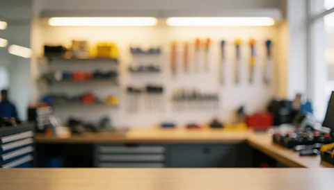 Arrière-plan flou d'un atelier de réparation avec des étagères à outils et des outils suspendus au mur, éclairé par une lumière chaude.