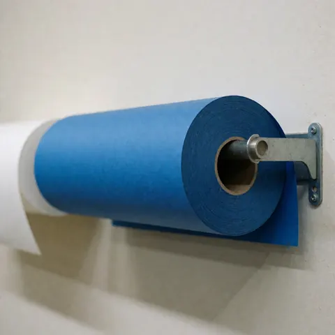 Rouleau de papier bleu fixé sur un support mural, à côté d'un rouleau blanc, sous un éclairage neutre pour la photographie de studio.