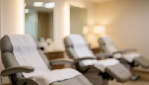 Arrière-plan flou d'un salon avec fauteuils couverts de serviettes blanches, miroirs et éclairage chaleureux beige neutre.