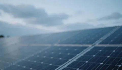 Fond de panneaux solaires photovoltaïques sous un ciel nuageux aux tons bleus doux, idéal pour textes ou bannières de services de réparation solaire.