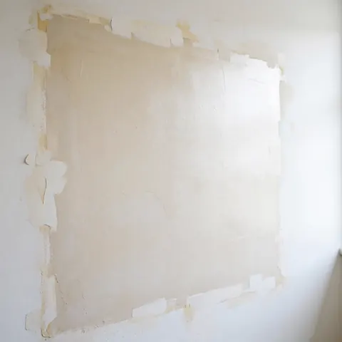 Mur de maison avec réparation invisible, texture lisse et ruban adhésif sur les bords, prêt à être peint, éclairage brillant et uniforme.