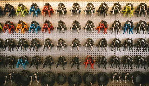 Mur métallique avec des composants de vélo disposés en rangées, servant de fond texturé pour un atelier de réparation.