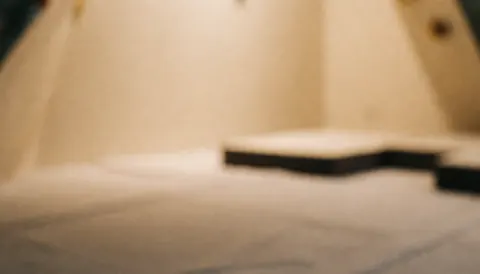 Fond doux et flou d'une salle d'escalade avec des murs beige et des tapis de mousse à l'arrière-plan, idéal pour les textes sur la récupération.