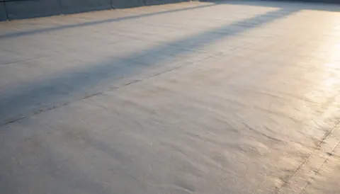 Fond de toit plat gris avec texture subtile et ombres douces de coucher de soleil, idéal pour textes commerciaux sans distractions.