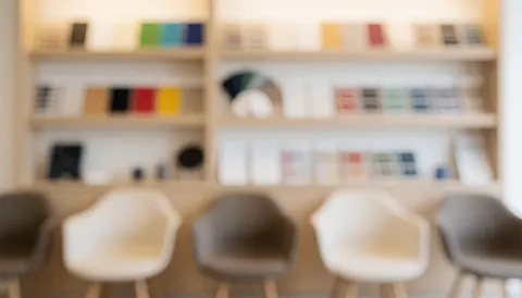 Arrière-plan flou montrant des chaises et des étagères contenant des panneaux d'échantillons de couleurs variées, créant une ambiance professionnelle et calme pour du texte commercial.