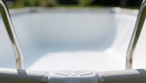 Fond de piscine avec garde-corps métallique et liner blanc, idéal pour textes. Scène propre et neutre avec lumière diffuse, parfaite pour promotions d'installation.