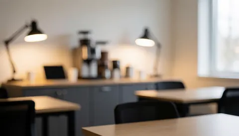 Vue d'une salle de classe avec tables, chaises, lampes et un coin café, créant une ambiance chaleureuse et relaxante pour l'étude.