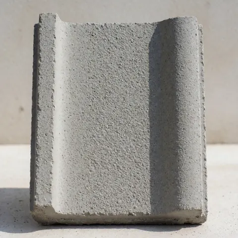 Tuile rectangulaire en béton gris présentant une texture granulaire détaillée, éclairée par la lumière naturelle.