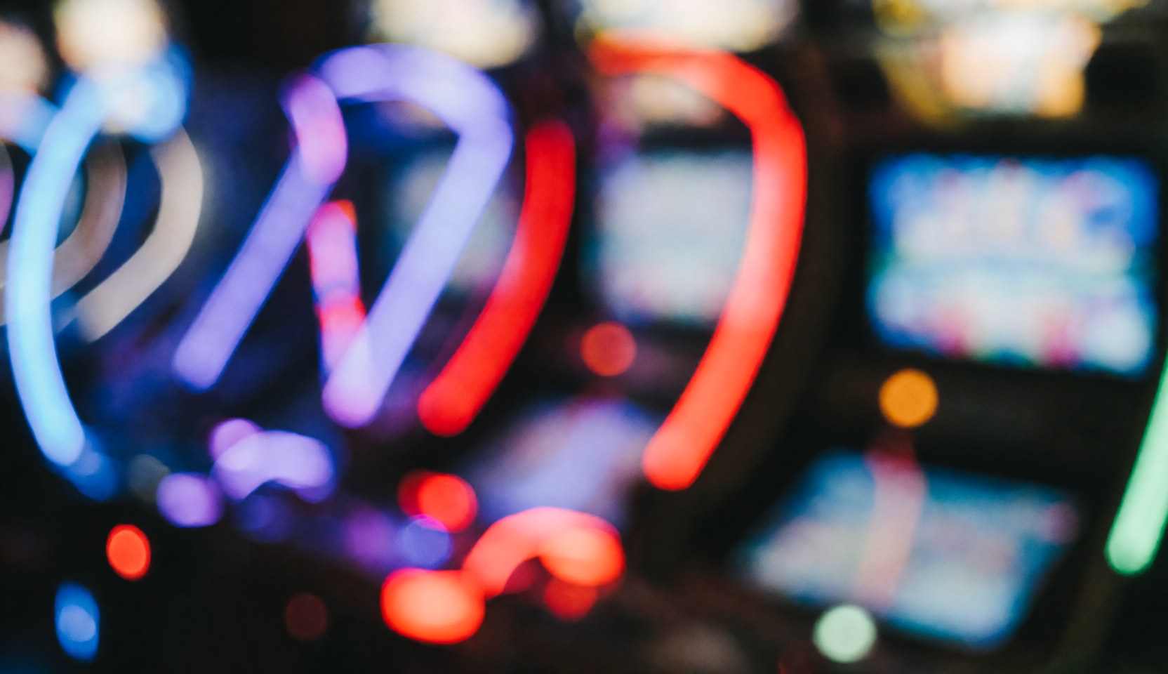 Fond abstrait d'un centre de loisirs avec des lumières de jeux en rouge, bleu et violet, effet bokeh, idéal pour du texte.
