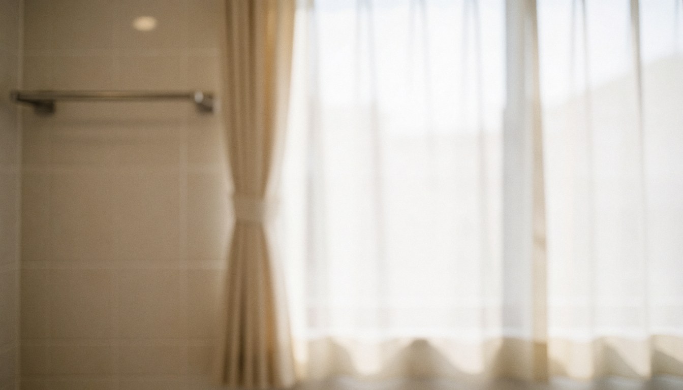 Fond flou d'une salle de bain avec murs carrelés, rideaux translucides et porte-serviettes métallique, idéal pour des textes professionnels.