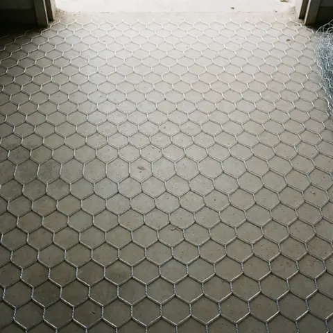 Vue de dessus d'une maille en fil galvanisé étendue sur un plancher en béton, matériau idéal pour la construction et la réparation de toitures.