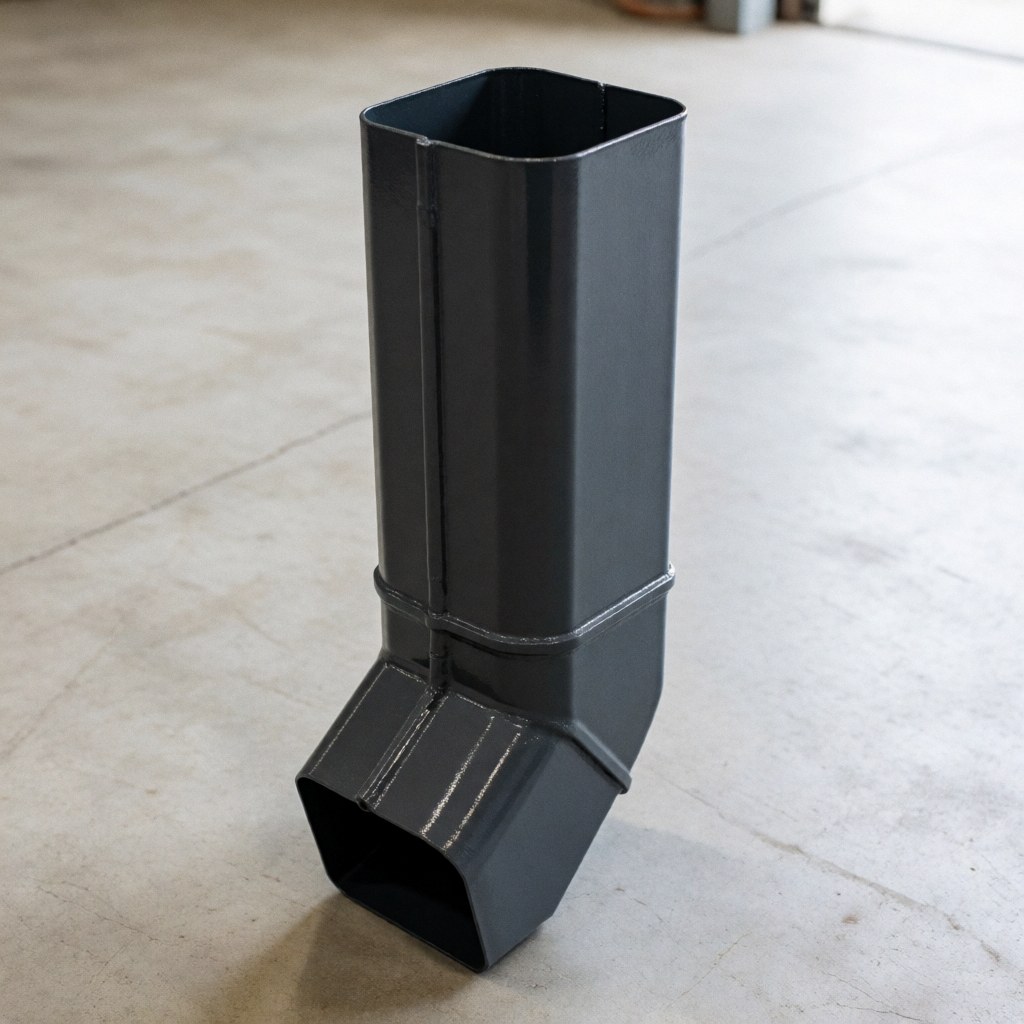 Tuyau d'évacuation métallique rectangulaire peint en gris anthracite posé sur un sol en béton, adapté aux projets de toitures et couvertures.