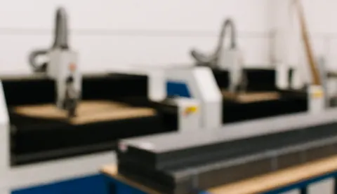 Arrière-plan flou d'un atelier de découpe de métal avec machines industrielles et piles d'acier, éclairage doux et professionnel pour superposer du texte