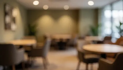 Arrière-plan flou d'une salle de réunion avec des tables rondes, des chaises, un éclairage chaleureux et des murs aux tons terre, idéal pour les événements.