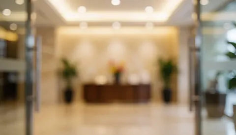 Entrée de lobby baignée d'une lumière chaude, décorations douces et tables d'accueil, servant de fond neutre pour vos messages commerciaux.