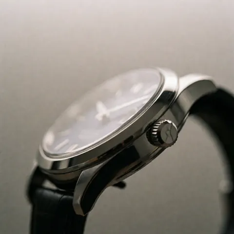 Montre de luxe avec verre saphir, bracelet en cuir noir, fond neutre, éclairage professionnel mettant en valeur sa finition polie et ses détails.