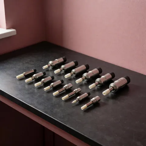 Association d'igniteurs piézoélectriques neufs pour cuisinières disposés sur un comptoir noir avec mur rose et éclairage doux.