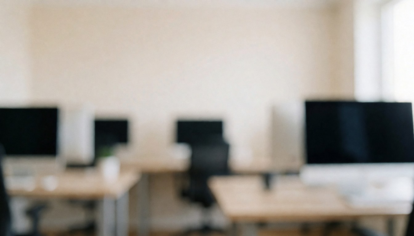 Arrière-plan flou d'un studio de photographie avec des bureaux et des écrans, éclairage doux et neutre, idéal pour ajouter du texte.