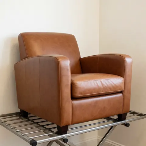Chaise en cuir marron restaurée et polie posée sur une étagère de séchage, avec un fond crème et un éclairage professionnel.