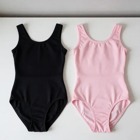 Deux collants de danse, un noir et un rose, posés à plat sur une surface blanche. La texture du tissu est visible, montrant sa qualité et son élasticité. L'éclairage est doux et diffus, sans ombres marquées, mettant en