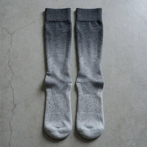 Chaussettes de sport avec un motif dégradé gris et une maille visible posées sur un sol en béton, idéales pour l'entraînement et la pratique sportive.
