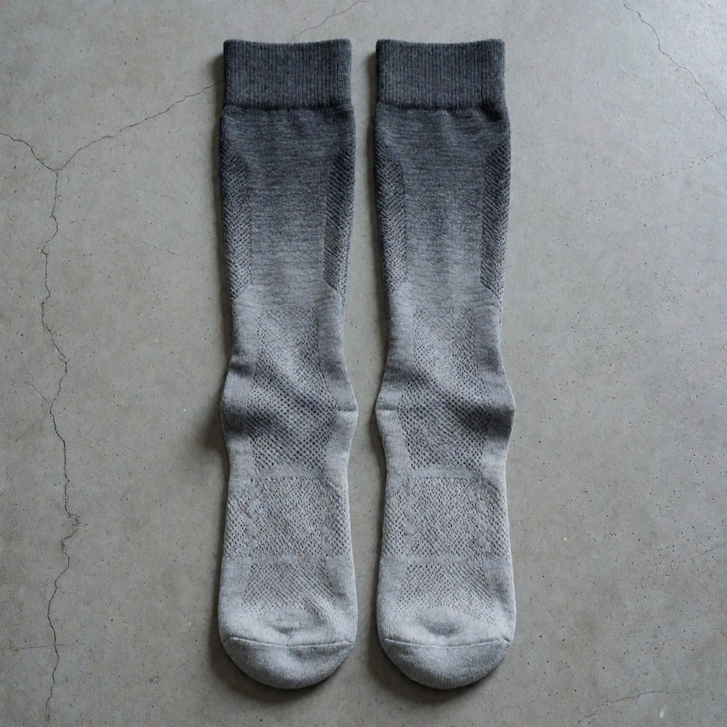 Chaussettes de sport avec un motif dégradé gris et une maille visible posées sur un sol en béton, idéales pour l'entraînement et la pratique sportive.