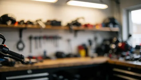 Fond flou d'un atelier de motocyclettes avec des outils et des pièces détachées, éclairage chaleureux et environnement ordonné pour textes.