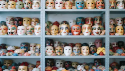 Étagères avec des masques de théâtre colorés en arrière-plan flou, offrant un fond neutre et doux idéal pour ajouter du texte ou des éléments graphiques.
