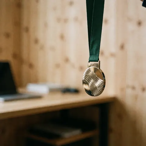 Médaille de montagne avec ruban vert accrochée dans un bureau aux murs en bois, idéale pour promouvoir des services d'entraînement cycliste.