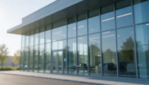 Façade moderne en verre avec reflets bleus et gris sous la lumière du matin, idéale pour illustrer les services de réparation de fenêtres.