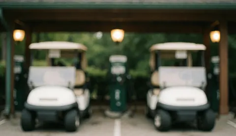 Deux chariots de golf blancs stationnés sous une structure avec des lumières chaudes, fond flou avec végétation verte, idéal pour textes commerciaux.