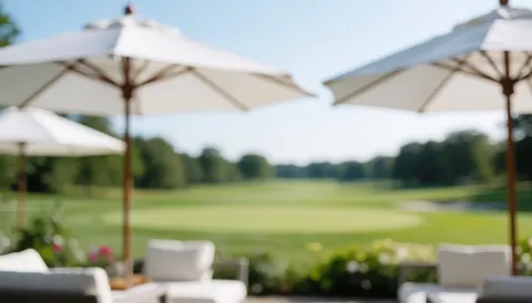 Terrasse de golf avec des ombrelles blanches et une pelouse verte floue, idéale pour du texte ou des événements en plein air.
