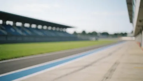Fond de piste de course avec herbe verte, gradas floues et lignes bleues, idéal pour textes et annonces.