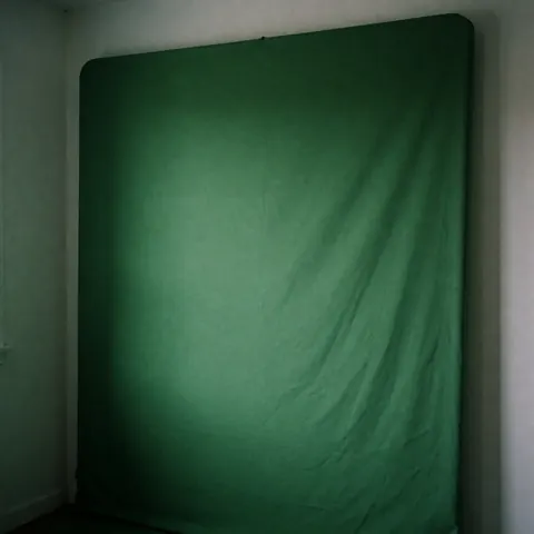 Fond vert uniforme idéal pour la composition numérique, avec un éclairage doux et des murs blancs dans un studio de photographie.