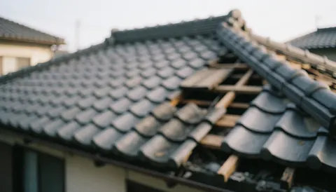 Toit de maison avec des tuiles manquantes et du bois exposé après une tempête, sur un fond flou pour texte commercial.