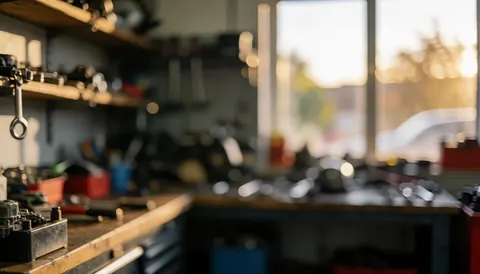 Arrière-plan d'atelier moto montrant des outils rangés sur des étagères, baigné par la lumière dorée du coucher de soleil, idéal pour illustrer des services de réparation.