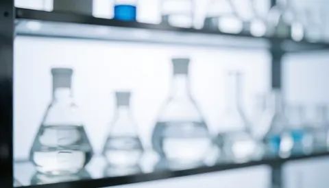 Fond de laboratoire avec des flacons en verre flous, des étagères métalliques et une lumière blanche froide, idéal pour des textes corporatifs.