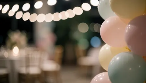 Colonne de ballons pastels au premier plan avec un arrière-plan flou aux lumières chaudes et tables d'événement, idéal pour du texte publicitaire.