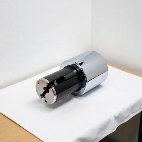 Cylindre de serrure de haute sécurité avec finition chromée et noyau noir posé sur un tissu blanc, éclairage clinique et murs blancs, produit de réparation de serrures.