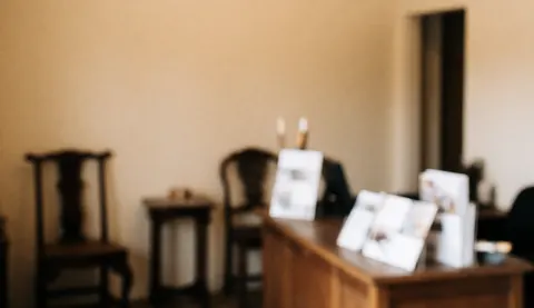 Vue de la réception d'un atelier de restauration avec des tables et chaises en bois sur fond beige, brochures posées sur une table, ambiance calme et professionnelle.