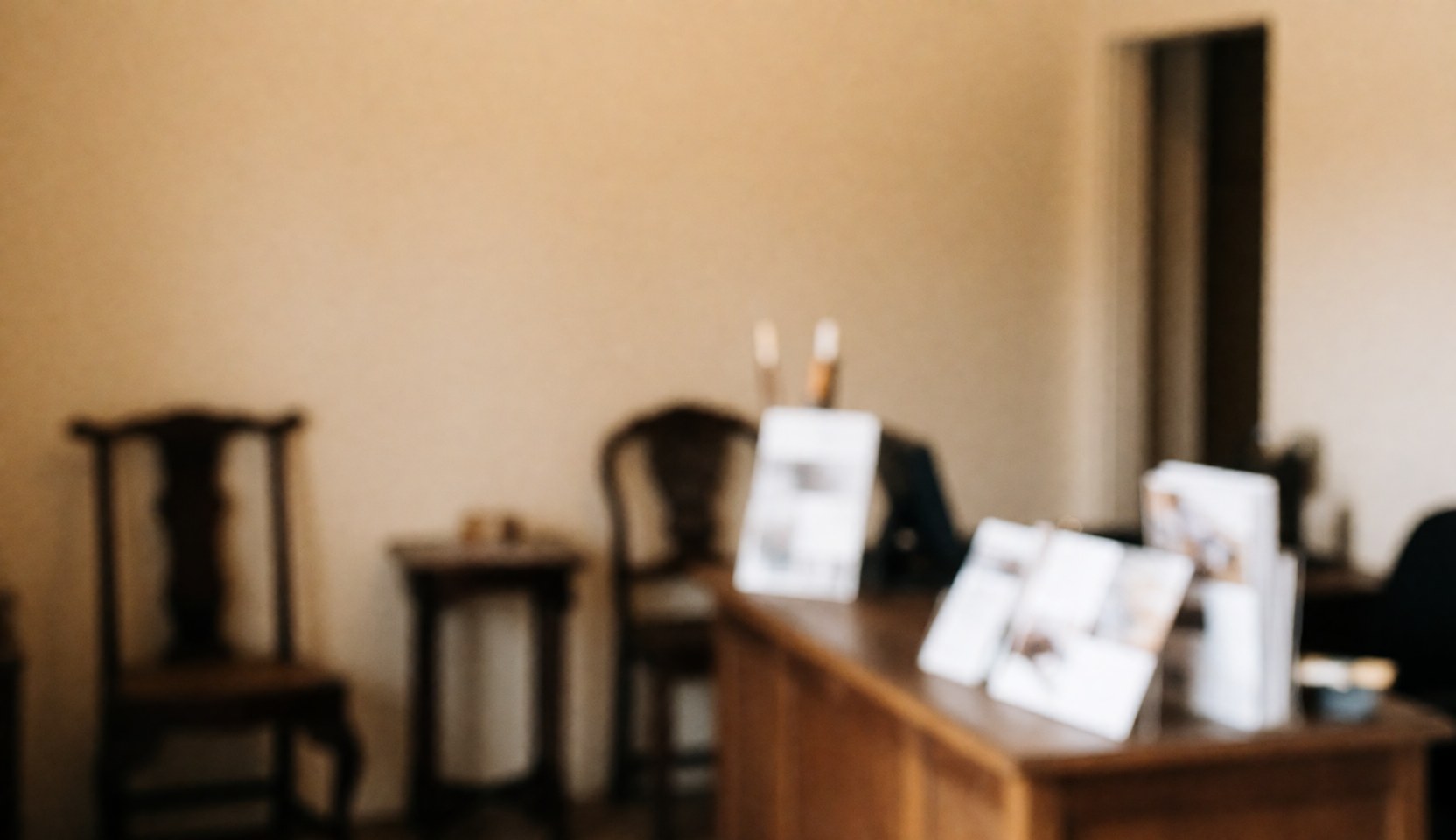 Vue de la réception d'un atelier de restauration avec des tables et chaises en bois sur fond beige, brochures posées sur une table, ambiance calme et professionnelle.
