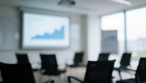 Fond professionnel de salle de réunion avec chaises noires et écran projeté montrant des graphiques d'analyse, idéal pour du texte sur la planification stratégique.