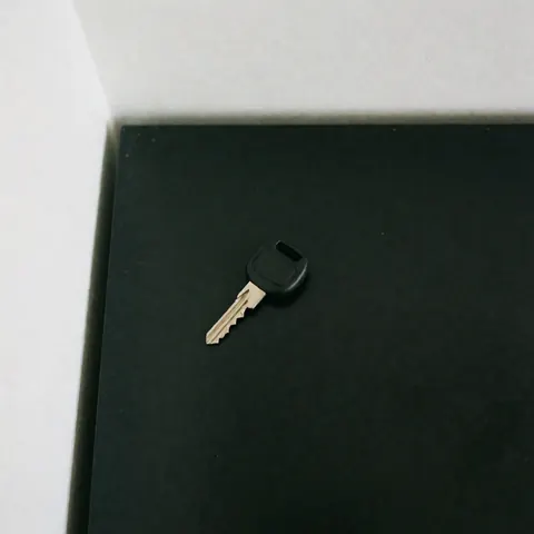 Clé de voiture avec manche noir et dents métalliques, posée sur une surface noire propre et éclairée doucement, idéale pour un catalogue de services de transport.