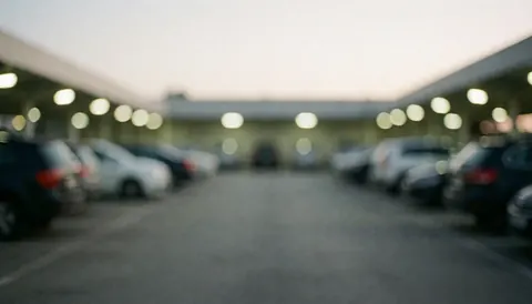 Fond professionnel de parking avec des véhicules stationnés et des lumières vives, idéal pour du texte commercial, évoquant un environnement sûr et ordonné.