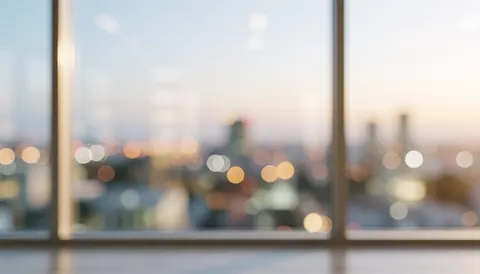 Vue à travers une fenêtre de bureau montrant une ville en arrière-plan flou avec des lumières chaudes créant une atmosphère sereine, idéale pour illustrer la propreté et le travail professionnel.