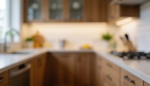 Cuisine contemporaine dotée d'armoires en bois, d'un plan de travail blanc et d'un éclairage ambiant chaleureux sur un fond flou adapté à l'intégration de textes commerciaux.