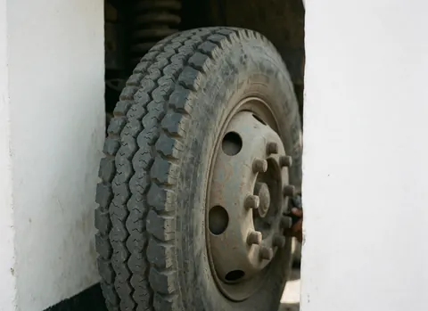 Gros plan sur une roue de camion montrant le dessin du pneu, des détails métalliques et des murs blancs. Idéal pour les entreprises de transport et de logistique.