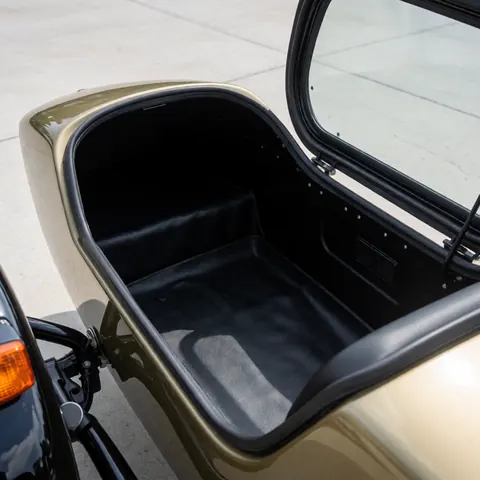 Intérieur du coffre d'attelage latéral de moto-taxi avec siège noir, porte ouverte sur sol en béton, propre et prêt au transport.